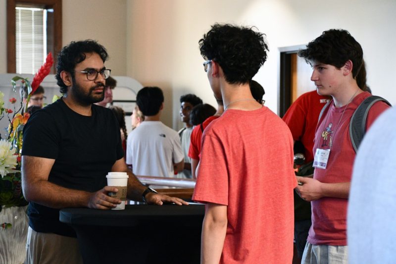 Man, at left, speaks to two students.