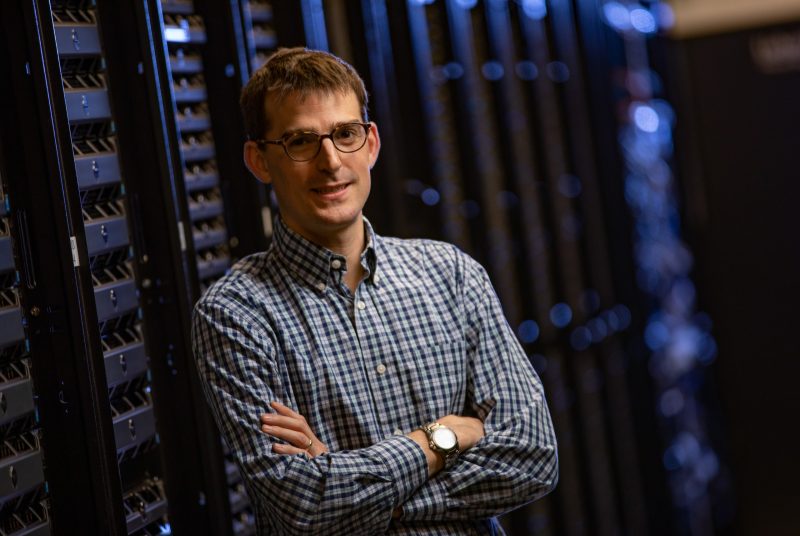 A man standing in front of a wall of data drives
