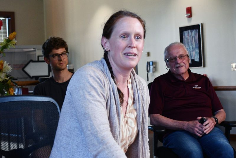 Women on chair with two men in background.