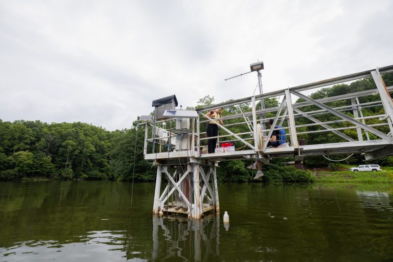 Students standing on a bridge in a reservoir, gathering information from their data equipment.